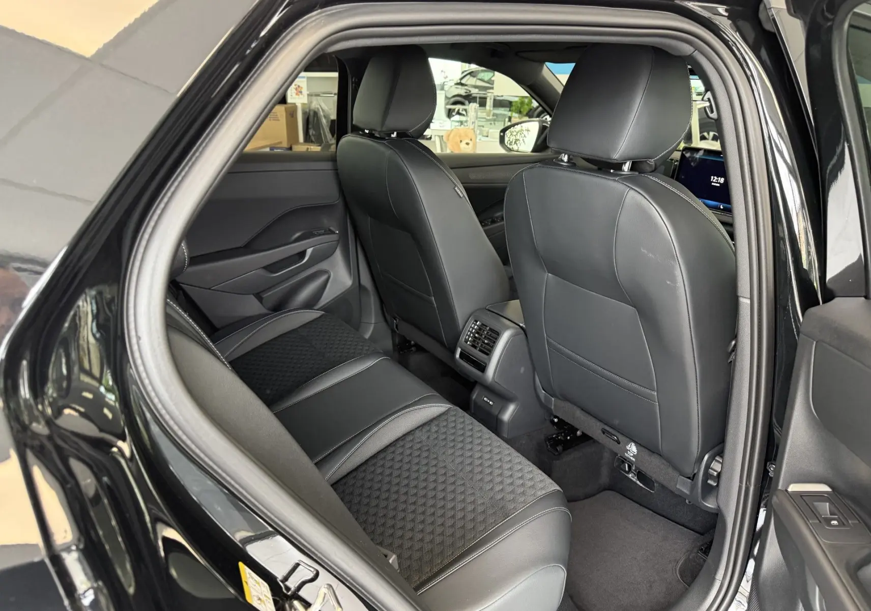 Vue intérieure côté arrière droit du Volkswagen T-Roc R-Line noir intense 2026, montrant les sièges en cuir et tissu avec console centrale.