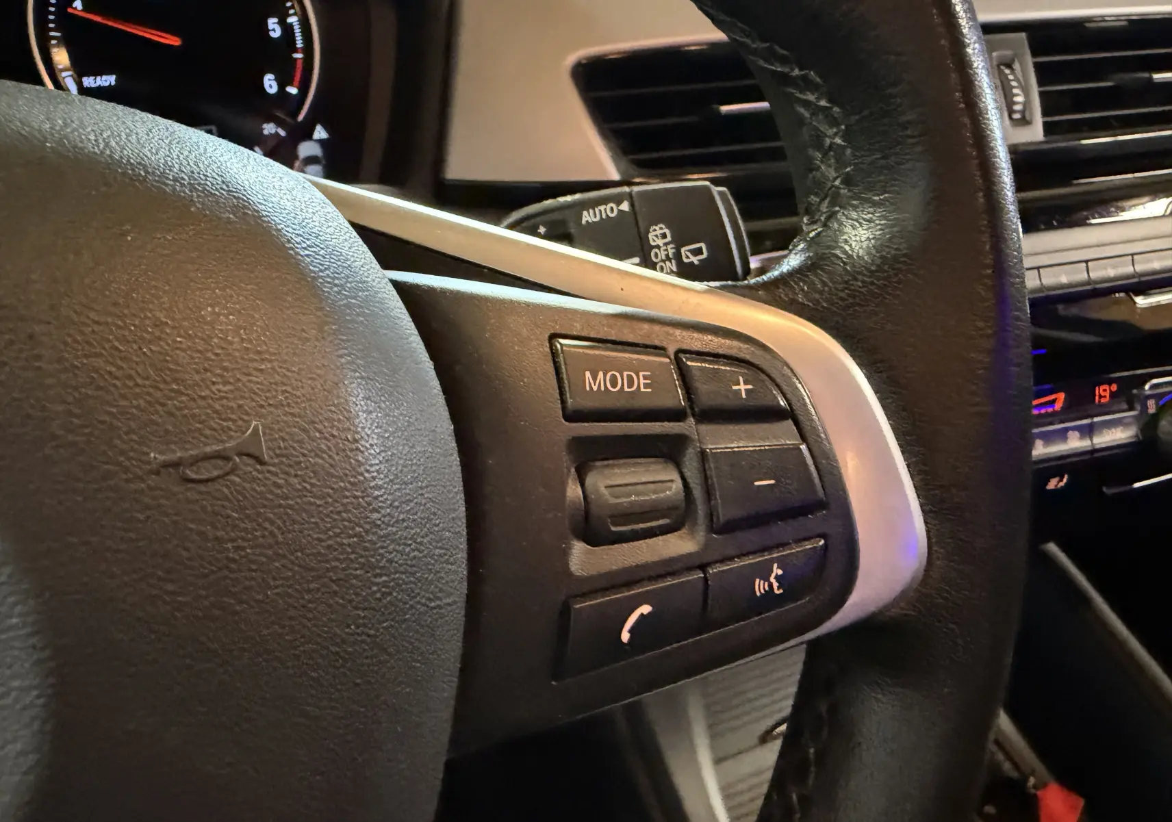 Gros plan sur le volant noir du BMW X1 F48 2019, avec commandes audio et téléphone côté droit.