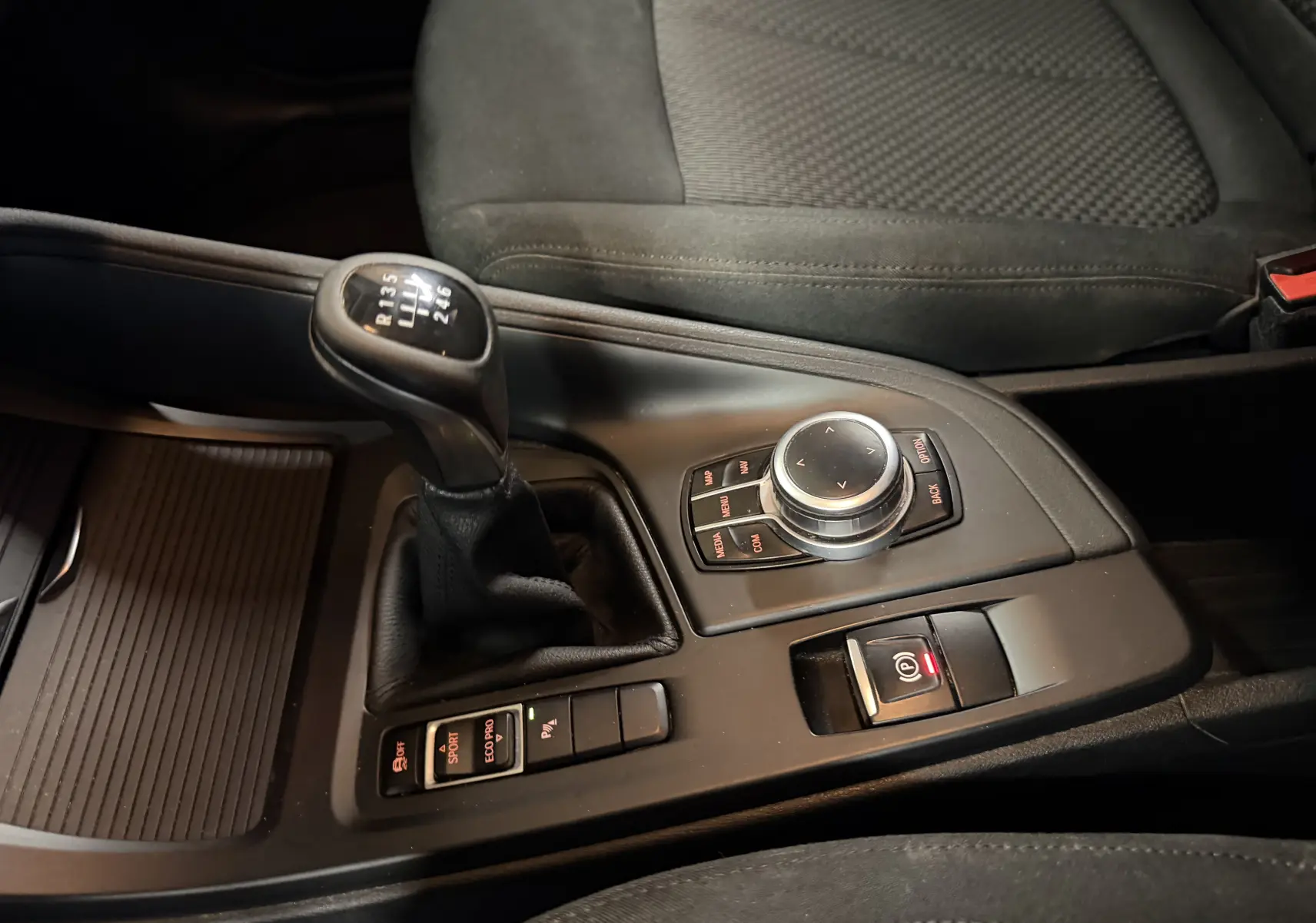Vue rapprochée de la console centrale noire d’une BMW X1 2019 avec levier de vitesse manuel et commandes iDrive.
