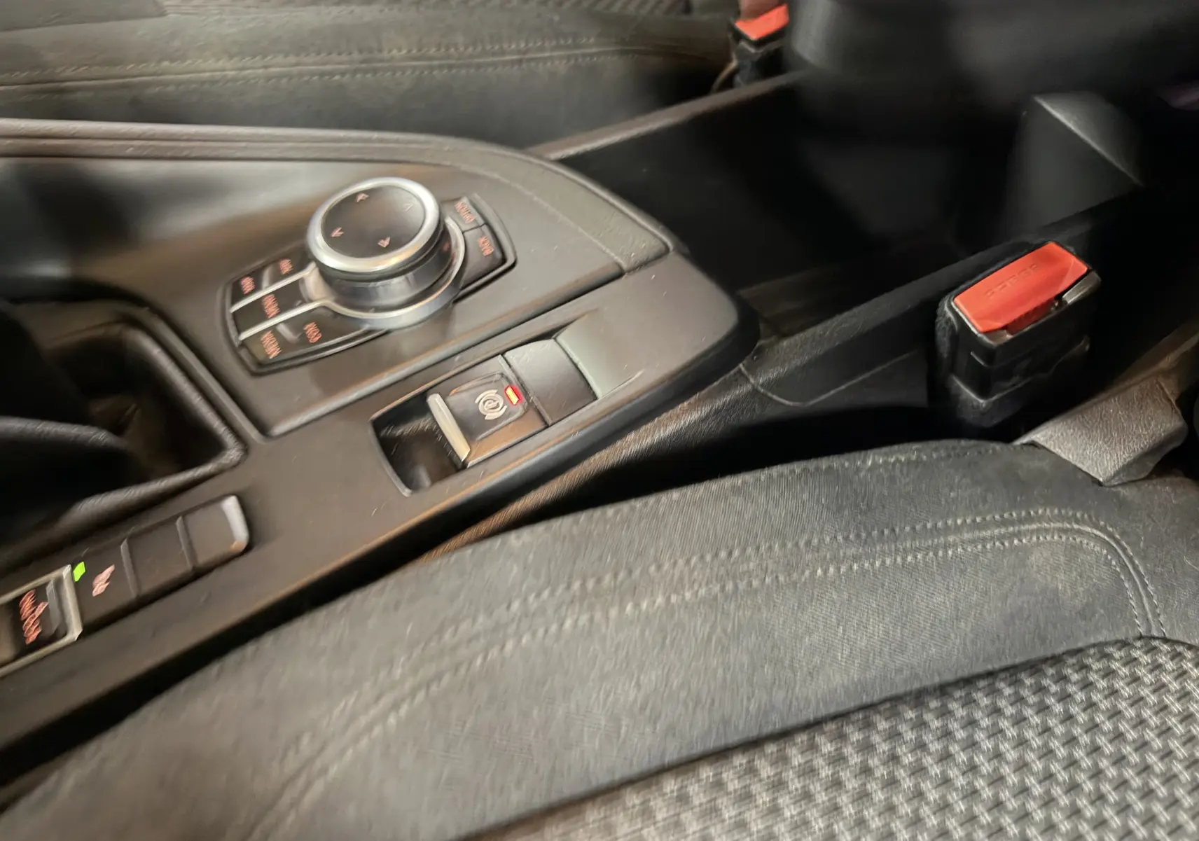Détail de la console centrale noire du BMW X1 F48 2019, avec molette de contrôle et frein à main électronique.
