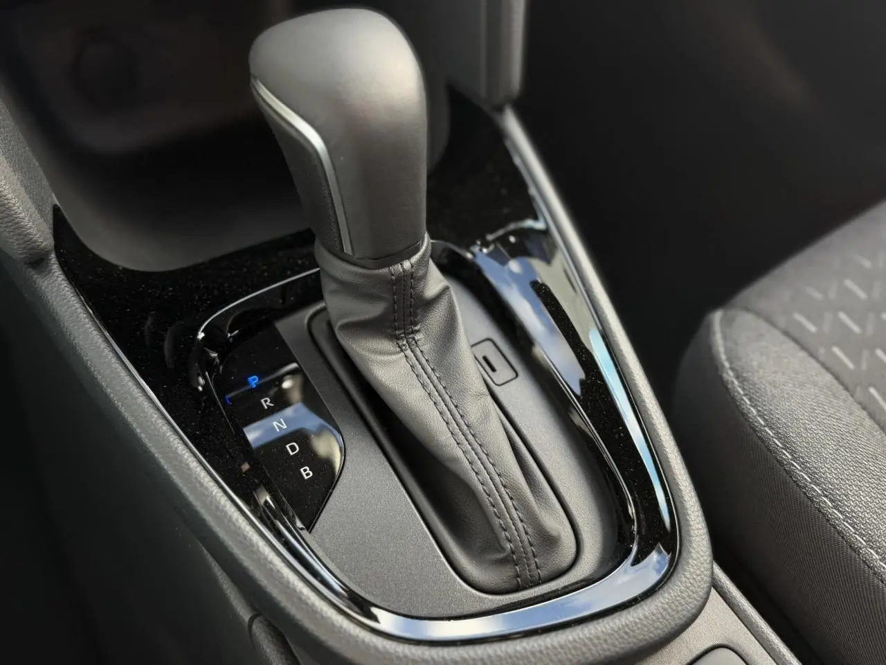 Gros plan sur la commande de la boîte automatique cuir dans l’habitacle sombre de la Toyota Yaris Cross 2026.