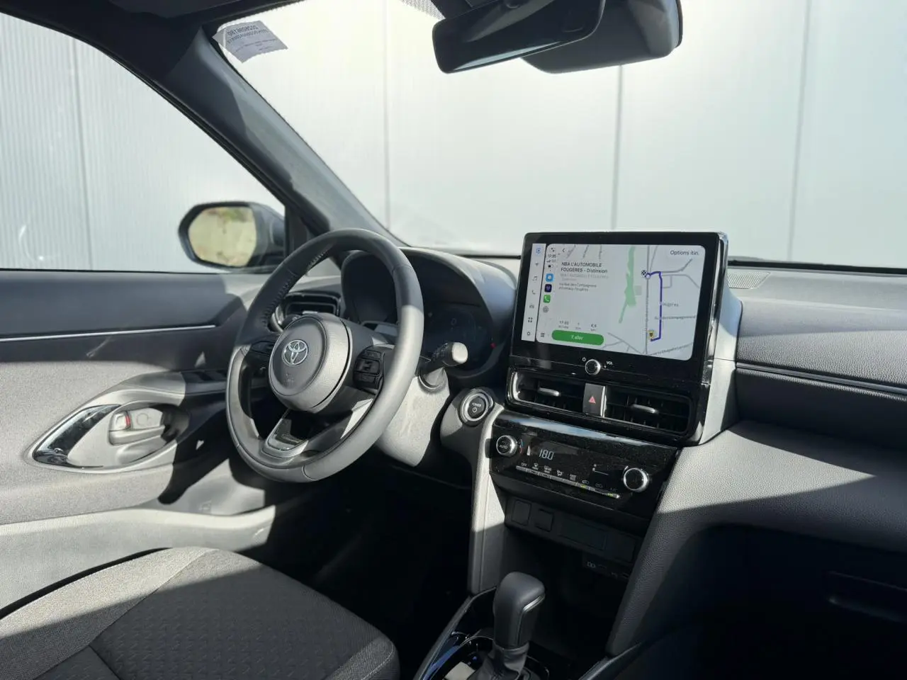 Intérieur de la Toyota Yaris Cross 2026 en gris, vue côté conducteur avec écran tactile GPS et volant multifonctions.
