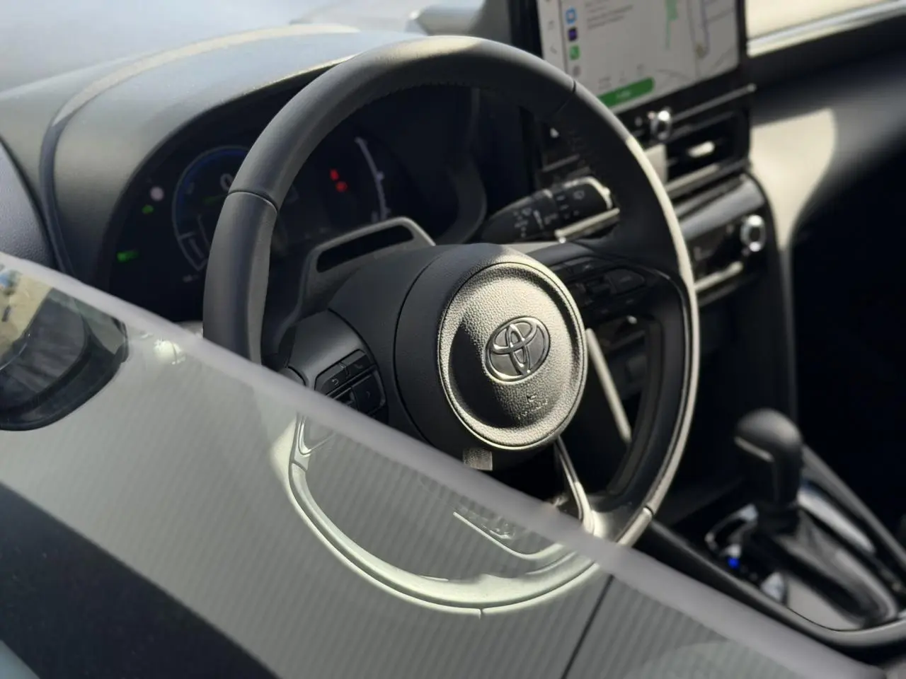 Vue rapprochée du volant en cuir et du tableau de bord numérique de la Toyota Yaris Cross 2026, intérieur noir.