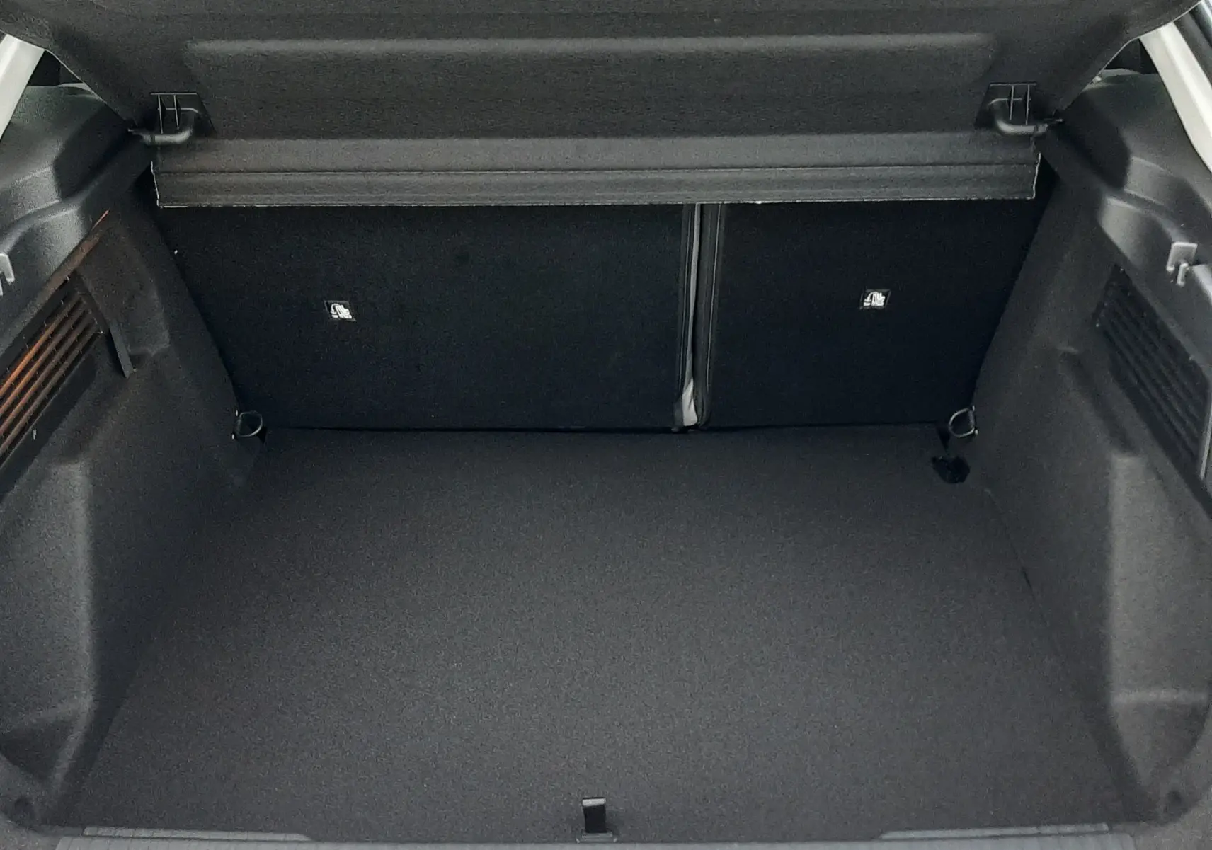 Coffre ouvert vu de l'arrière d'une Citroën C4 blanche, montrant un espace de chargement vide et propre.