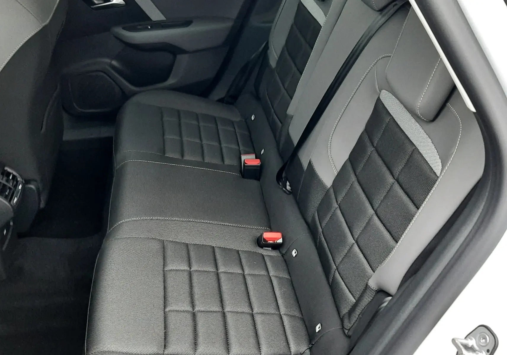 Vue intérieure arrière droite des sièges arrière gris foncé et clairs de la Citroën C4 blanche 2026 hybride.