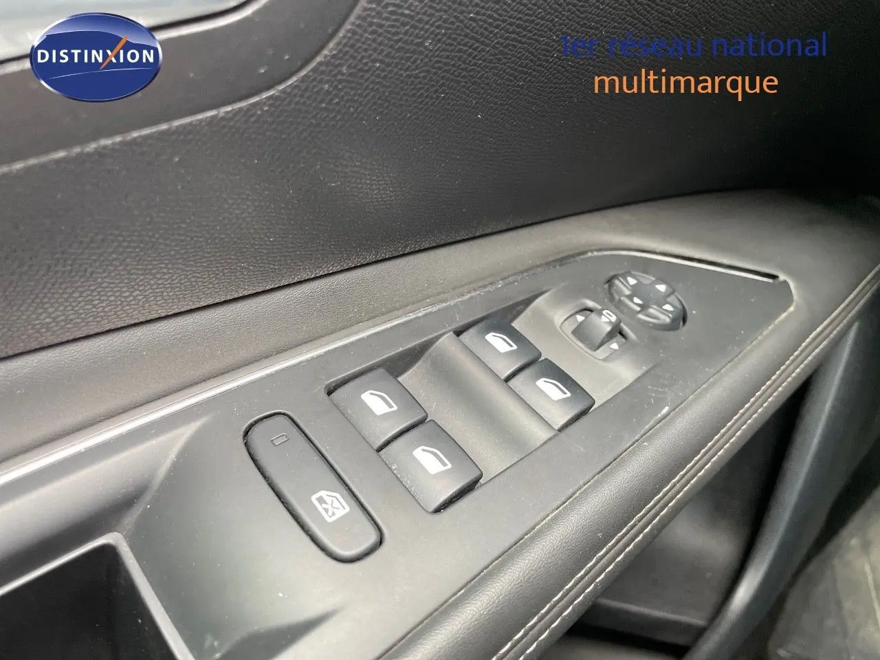Gros plan sur les commandes de lève-vitres et réglage des rétroviseurs sur la porte côté gauche d’un Peugeot 3008 gris.