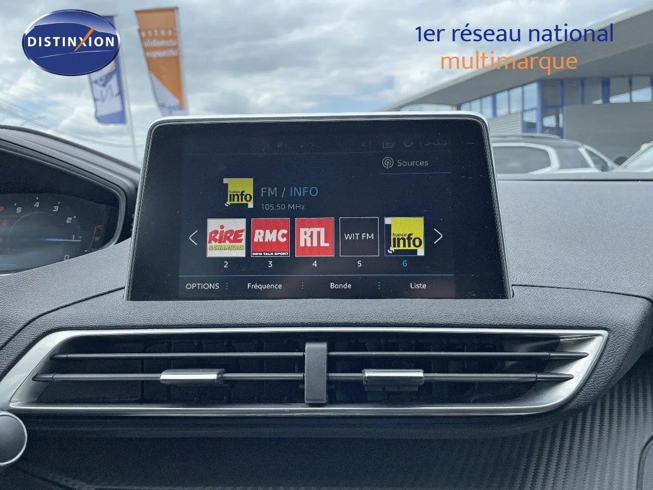 Écran tactile central du tableau de bord du Peugeot 3008 gris Artense, affichant les stations radio FM en extérieur showroom.