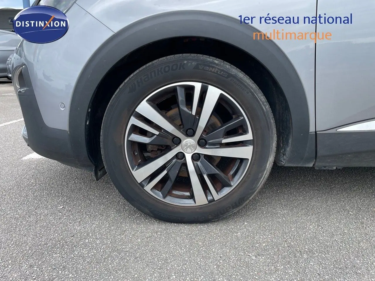Gros plan sur la roue avant droite du Peugeot 3008 gris Artense métal, avec jante alliage bicolore distinctive.