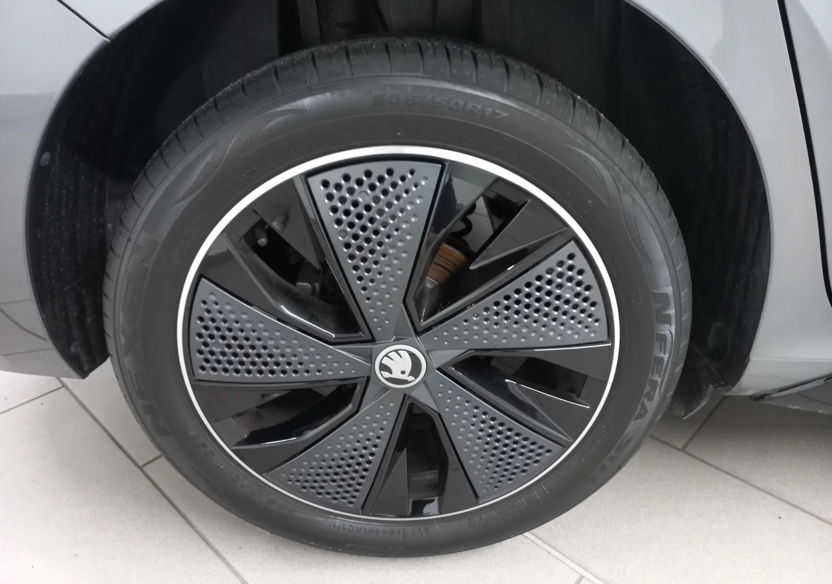 Gros plan sur la roue avant gauche d'une SKODA SCALA 2025 gris graphite avec jante noire au design perforé.