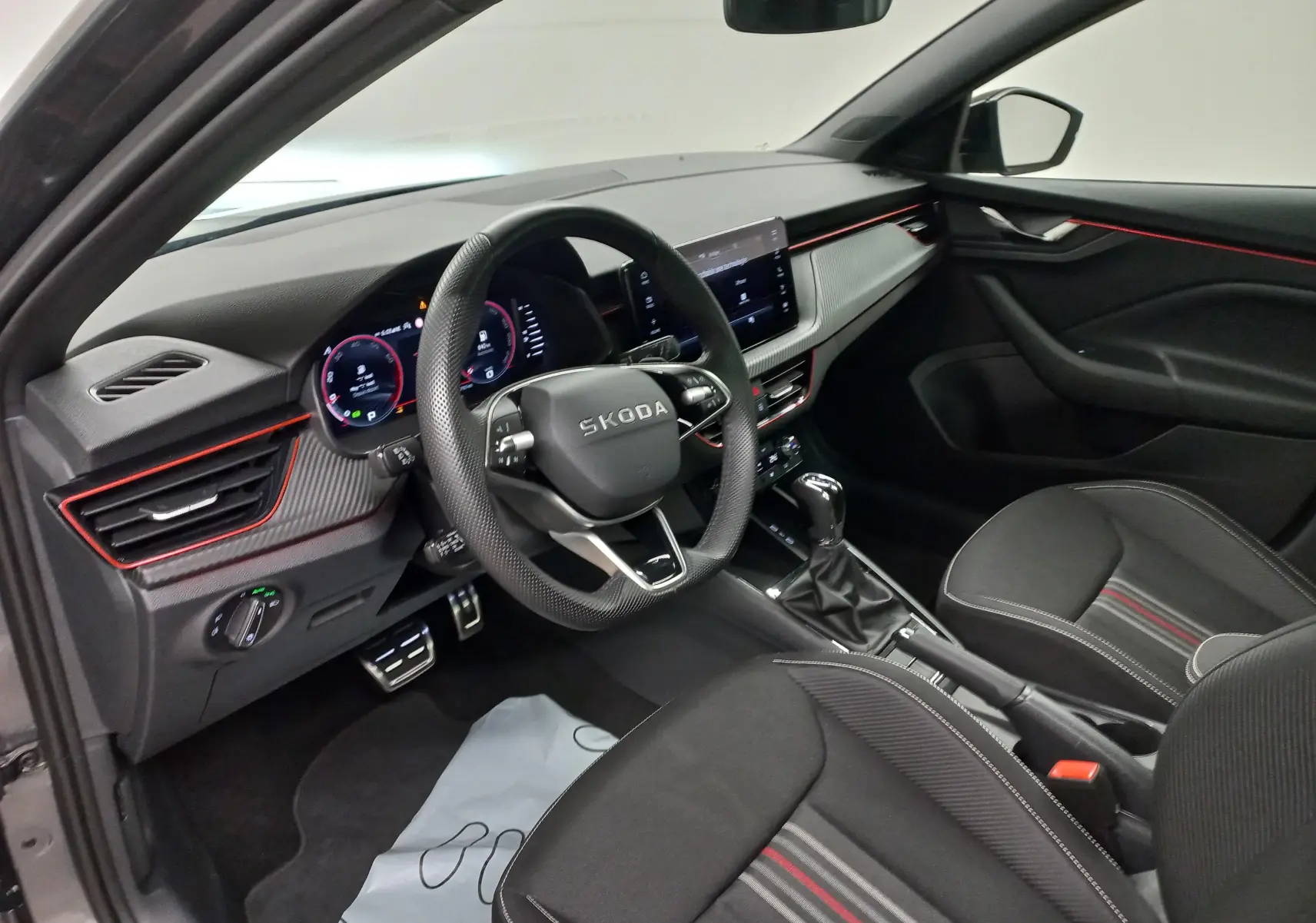 Intérieur côté conducteur du Skoda Scala 2025 gris graphite, avec tableau de bord moderne et éclairage rouge subtil.