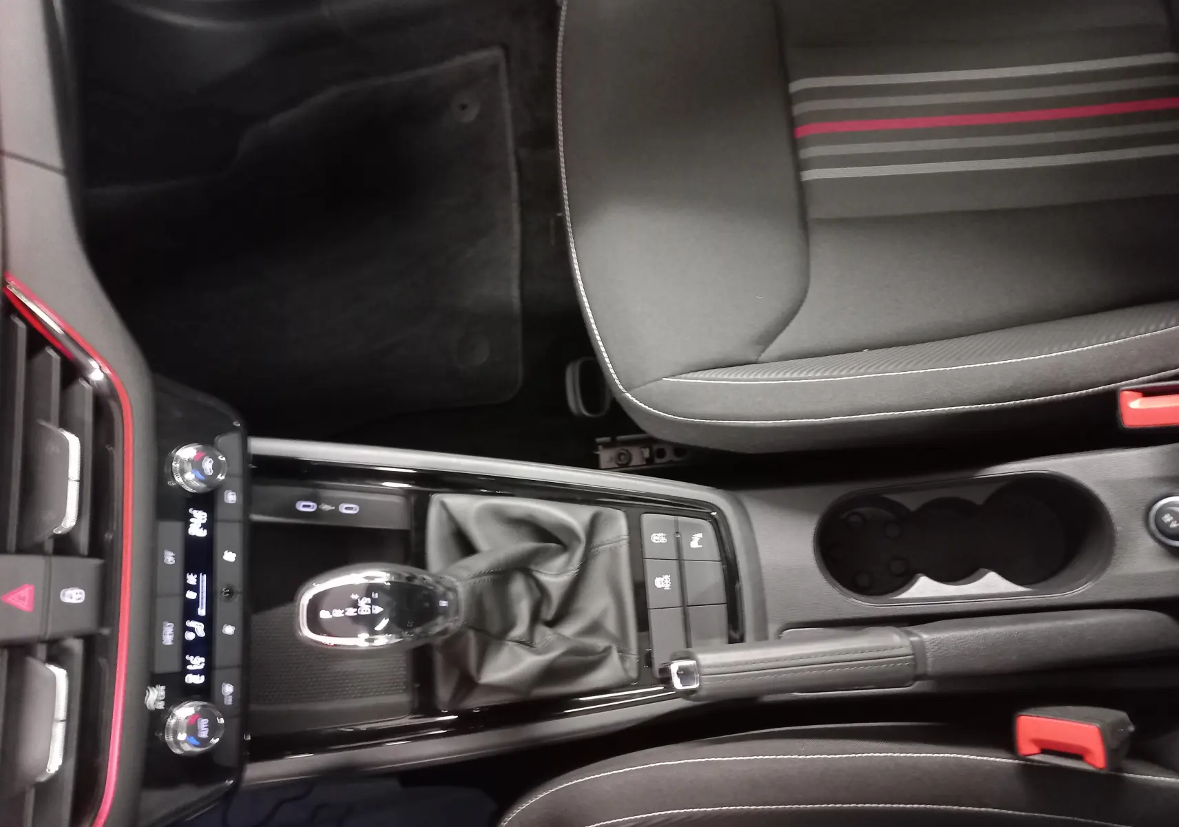 Vue plongeante sur la console centrale et le siège avant droit de la Skoda Scala 1.5 TSI Monte-Carlo avec surpiqûres rouges.