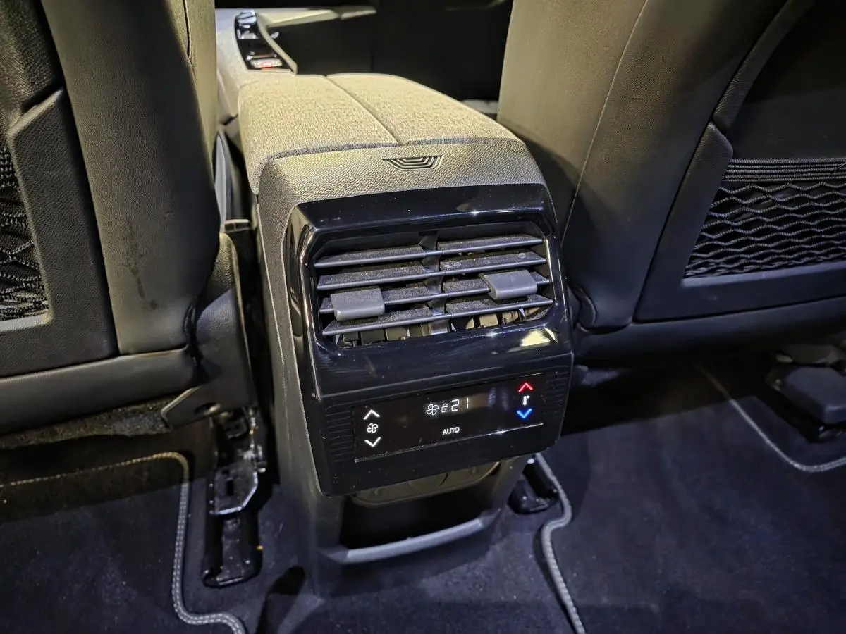 Vue rapprochée de la console centrale arrière du Peugeot 5008 gris, avec commandes de climatisation et aérateurs noirs.
