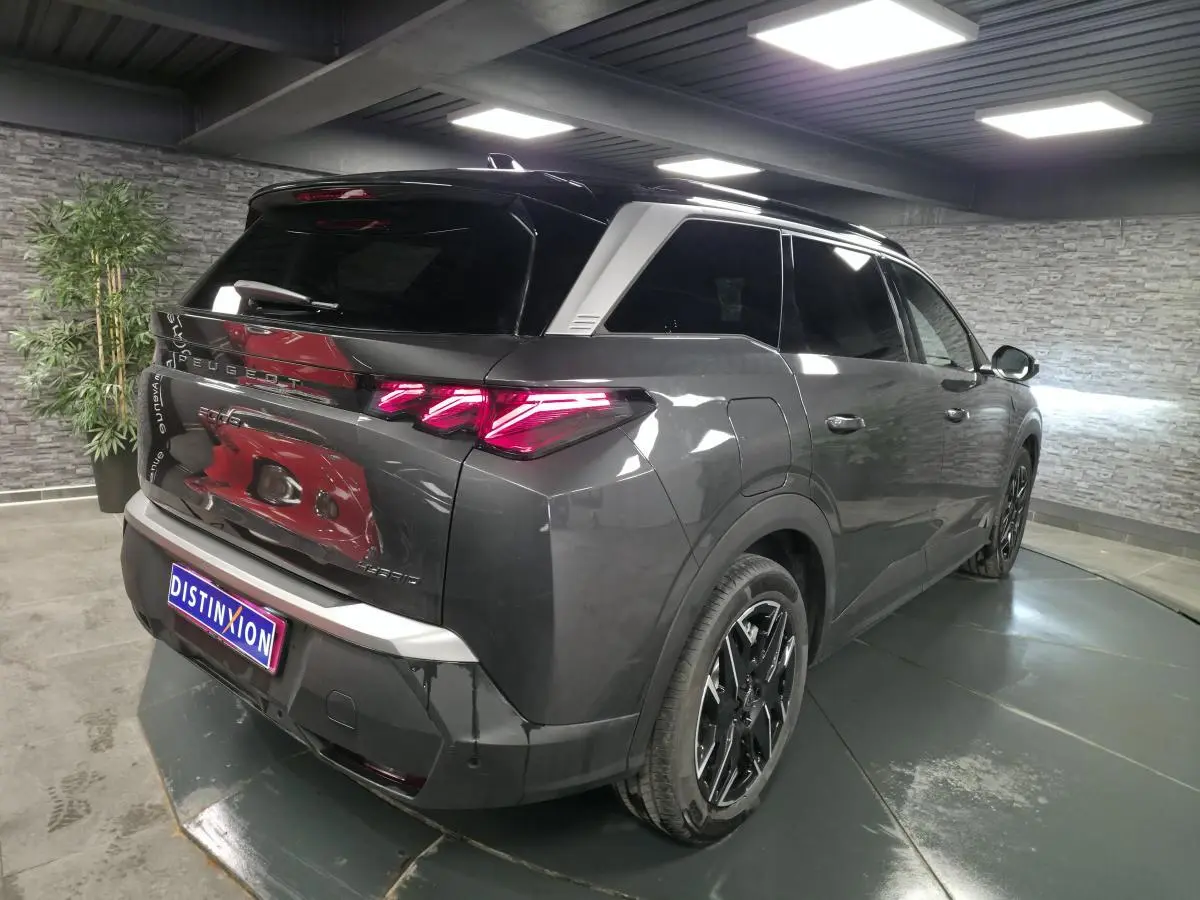 Vue 3/4 arrière droit du Peugeot 5008 gris métallisé avec feux arrière LED 3 griffes et jantes alliage noires.