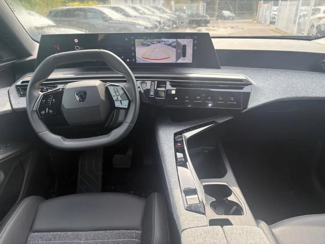 Intérieur du Peugeot 5008 Hybrid 2025 vu de face, tableau de bord moderne avec écran tactile et volant compact noir.