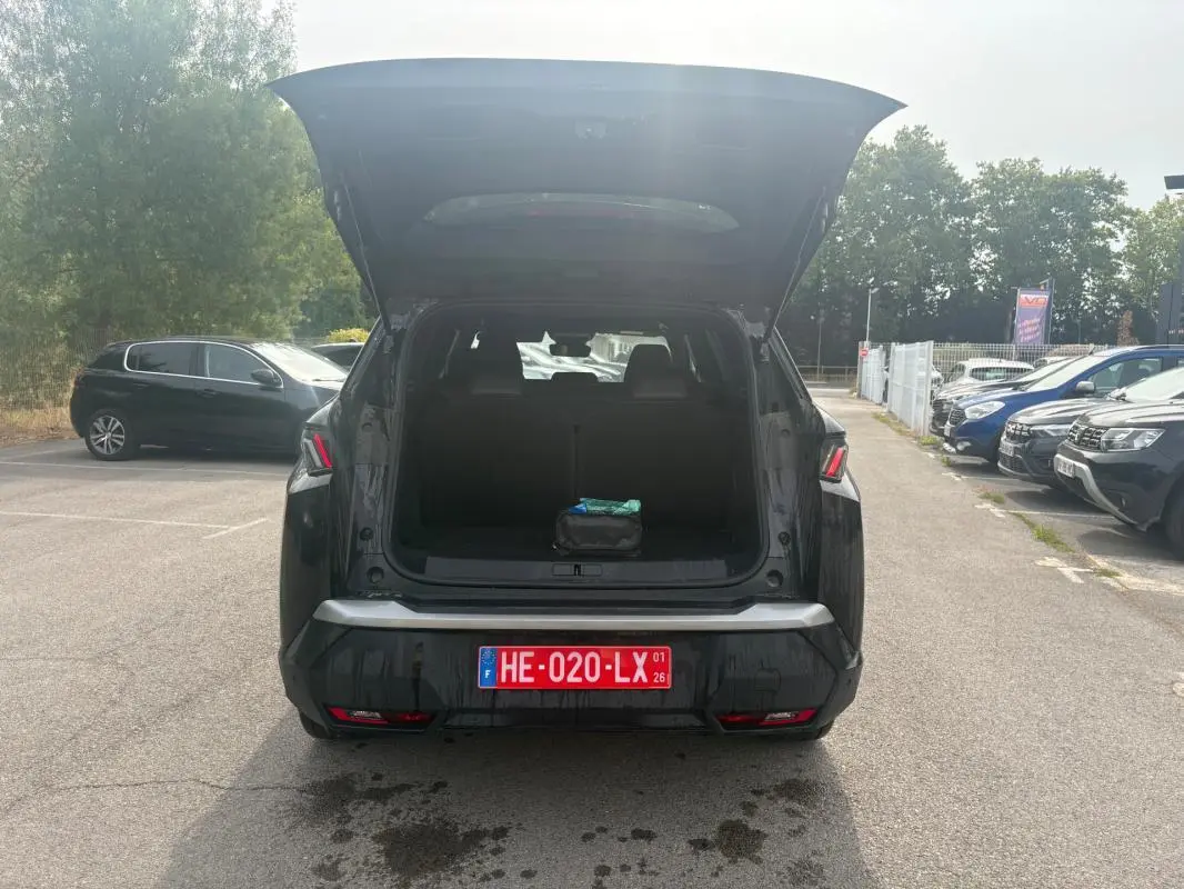Vue arrière d’un Peugeot 5008 noir 2025 avec coffre ouvert et plaque d’immatriculation rouge visible en extérieur.