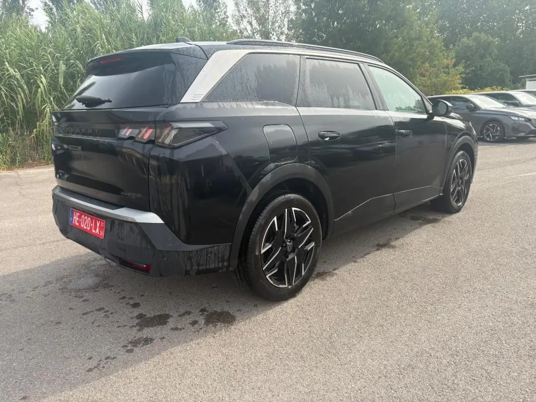 Peugeot 5008 Hybrid noir vue 3/4 arrière droit, avec jantes noires et détails chromés sur montant arrière.