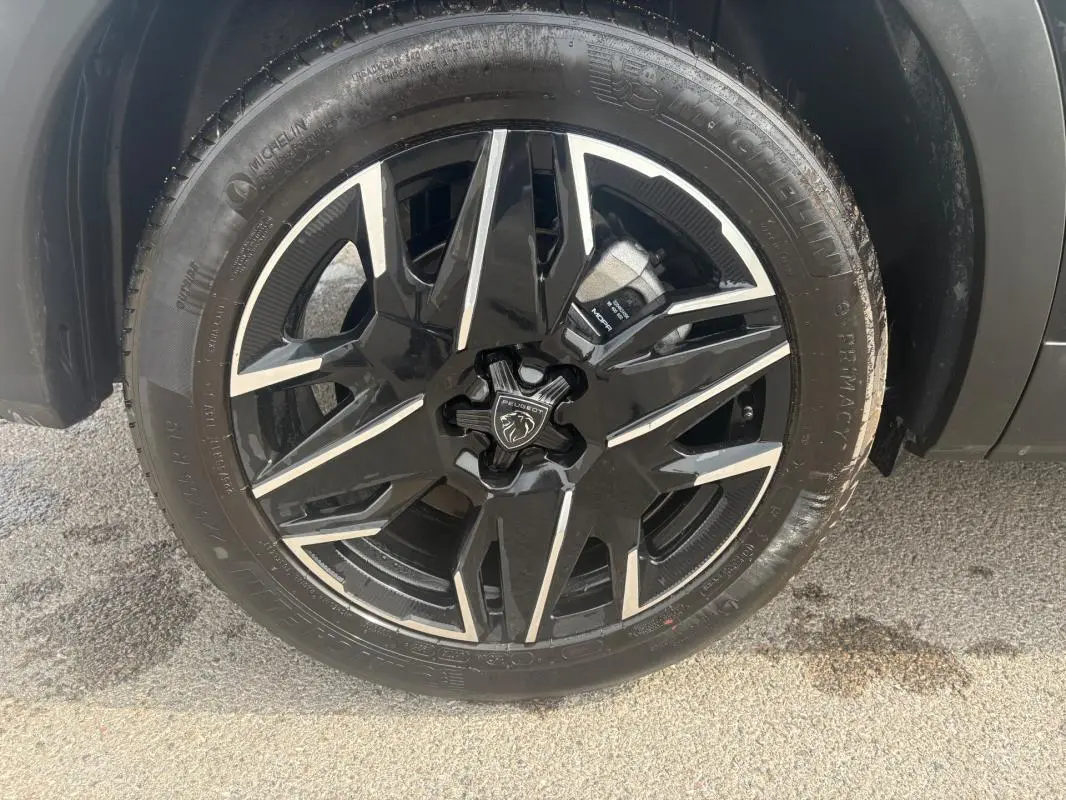 Gros plan sur la roue avant gauche du Peugeot 5008 noir 2025, avec jante alliage noire et argentée distinctive.
