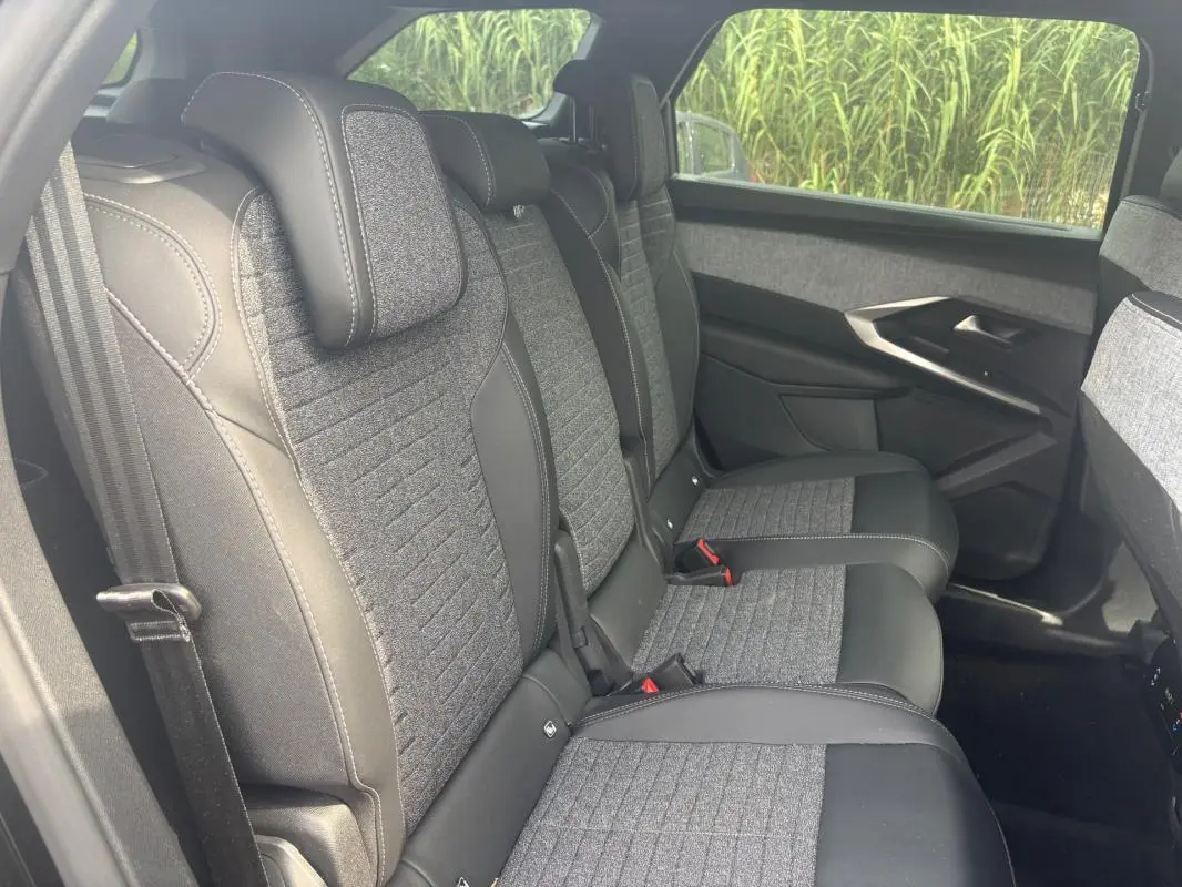 Vue côté droit de la banquette arrière du Peugeot 5008 Hybrid 2025, avec sellerie tissu gris et cuir noir.