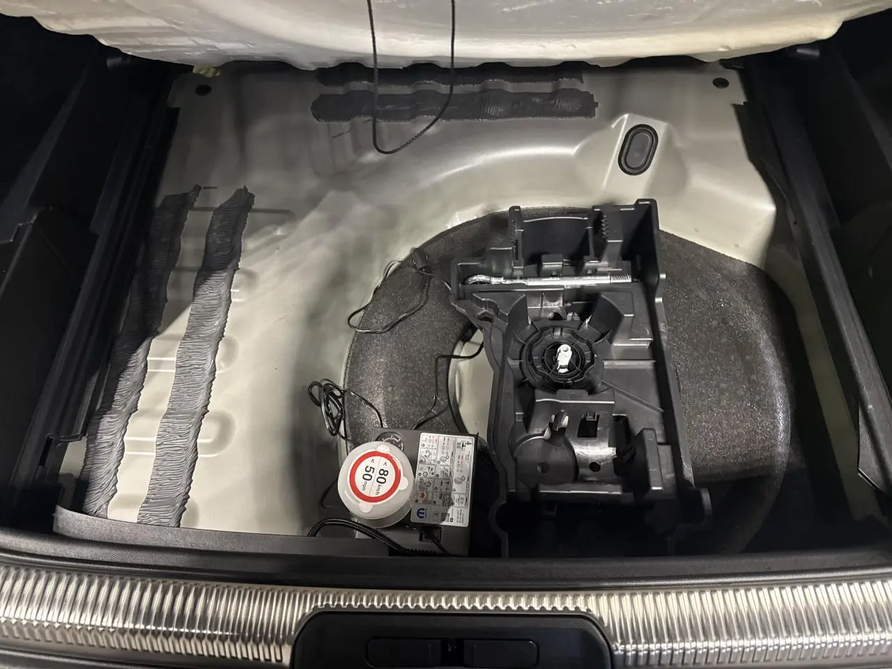 Coffre ouvert du DS7 Crossback gris montrant le rangement sous plancher avec kit de dépannage et compresseur.