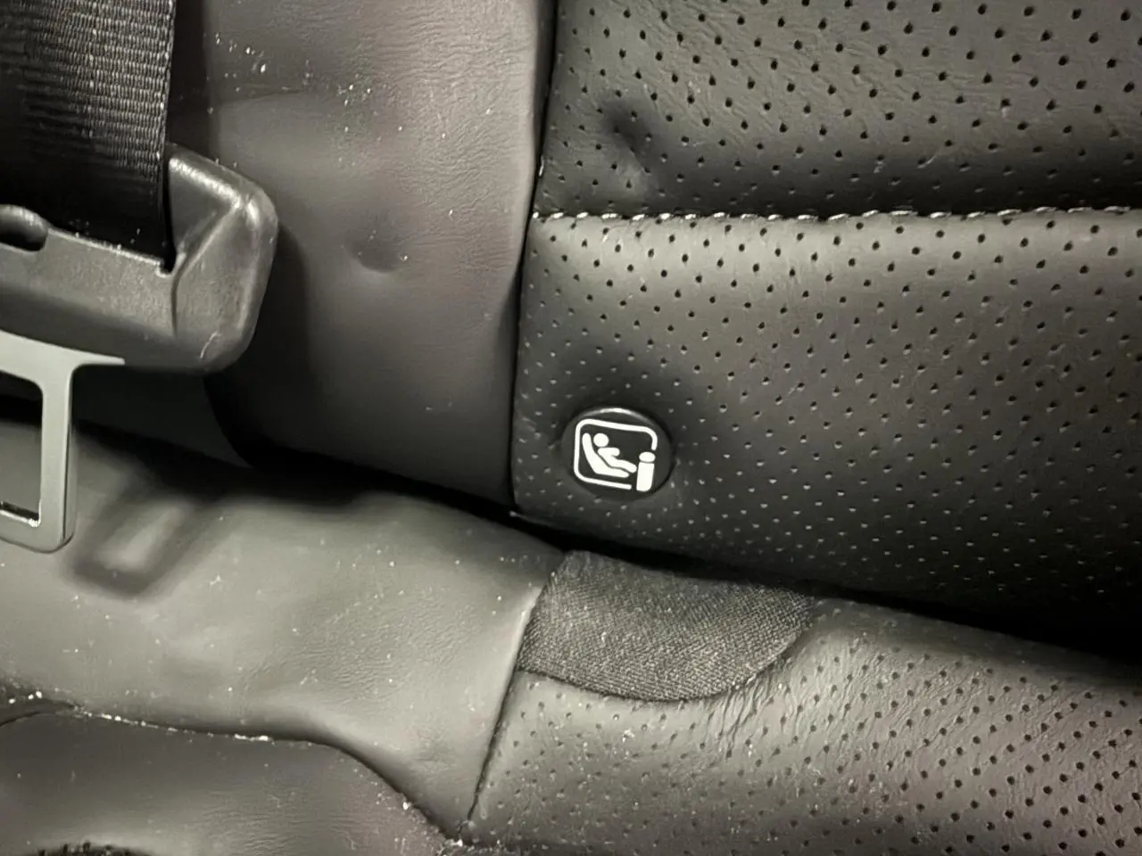 Gros plan sur la fixation ISOFIX sur la banquette arrière en cuir noir perforé du DS7 Crossback gris.