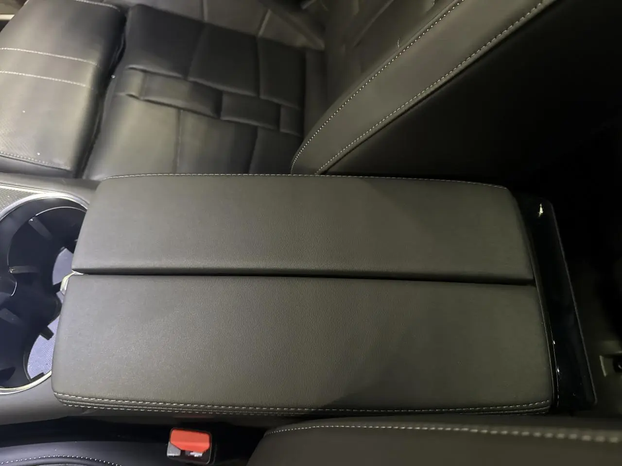 Gros plan sur l'accoudoir central en cuir noir du DS7 Crossback 2025, avec siège et porte-gobelets visibles.