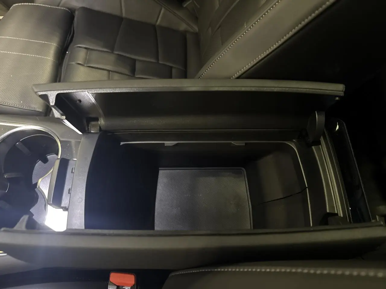 Vue rapprochée de la console centrale ouverte avec rangement intérieur noir du DS7 Crossback gris, sièges en cuir visibles.