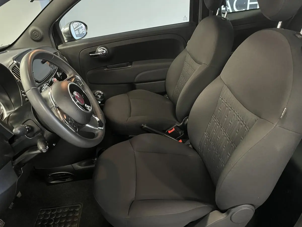 Intérieur avant noir de la Fiat 500 2023, vue côté conducteur avec sièges et volant en tissu sombre.