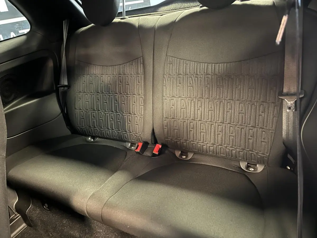 Banquette arrière noire de Fiat 500 2023 avec motifs FIAT embossés et ceintures de sécurité visibles.