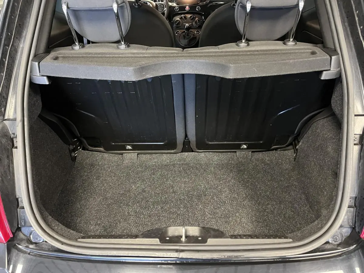 Coffre ouvert vu de l'arrière d'une Fiat 500 noire, montrant la banquette arrière et la surface de chargement.