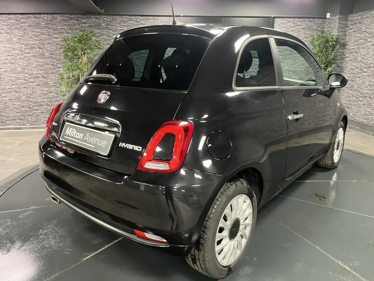 Vue 3/4 arrière droite d'une Fiat 500 noire hybride 2023 avec feux arrière LED et jantes alliage claires.
