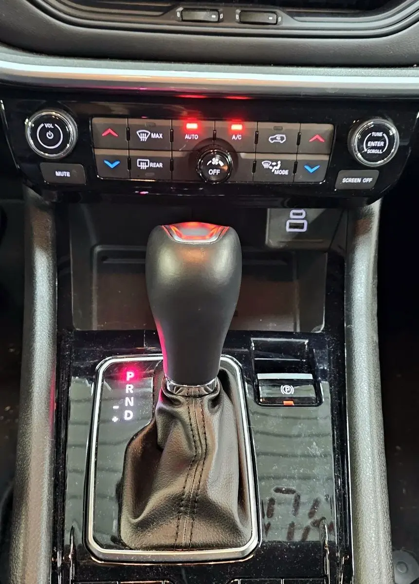 Gros plan sur la console centrale noire du Jeep Compass 2023, mettant en valeur le levier de vitesse automatique et les commandes climatiques.