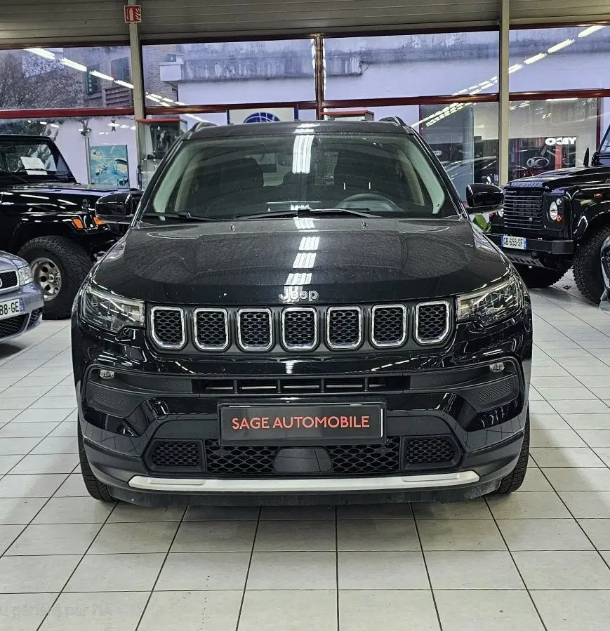 Vue frontale d'un Jeep Compass noir 2023 dans un showroom, mettant en valeur sa calandre distinctive à sept fentes.