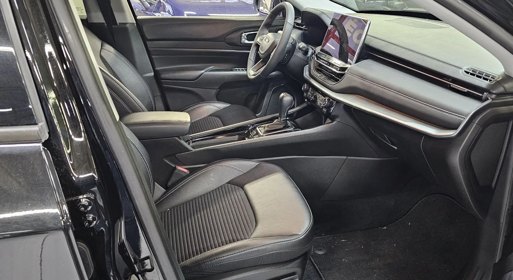 Intérieur noir du Jeep Compass 2023 vu côté conducteur, avec sièges cuir et tableau de bord moderne équipé d'un écran tactile.