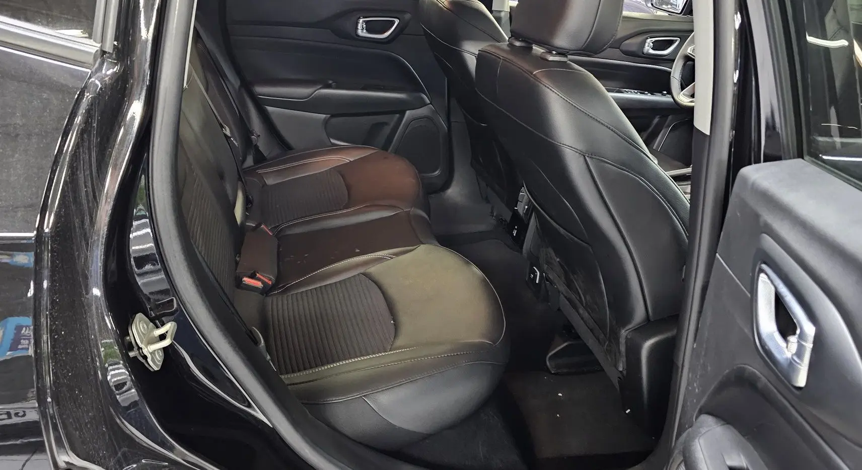 Vue intérieure côté droit sur les sièges arrière en cuir noir du Jeep Compass 2023 avec portières ouvertes.