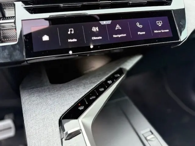Vue intérieure rapprochée du tableau de bord du Peugeot 3008 Hybrid 145 GT, avec écran tactile et inserts tissu Uziris gris.