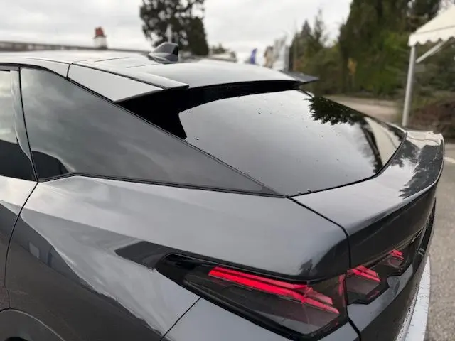 Vue 3/4 arrière droite du Peugeot 3008 Hybrid 145 GT en gris titane, soulignant les feux arrière LED et le toit noir brillant.