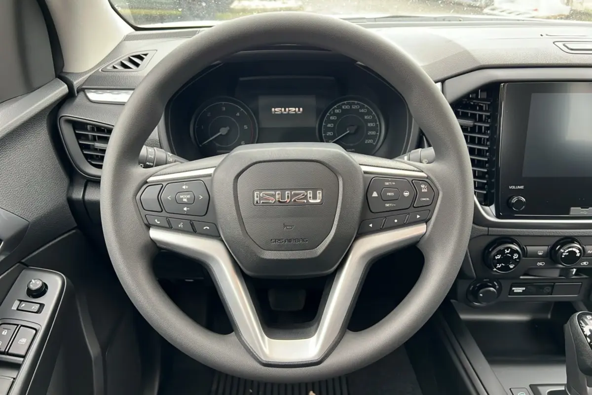 Vue intérieure centrée sur le volant multifonctions gris d'un Isuzu D-MAX 2026 avec tableau de bord et écran tactile.