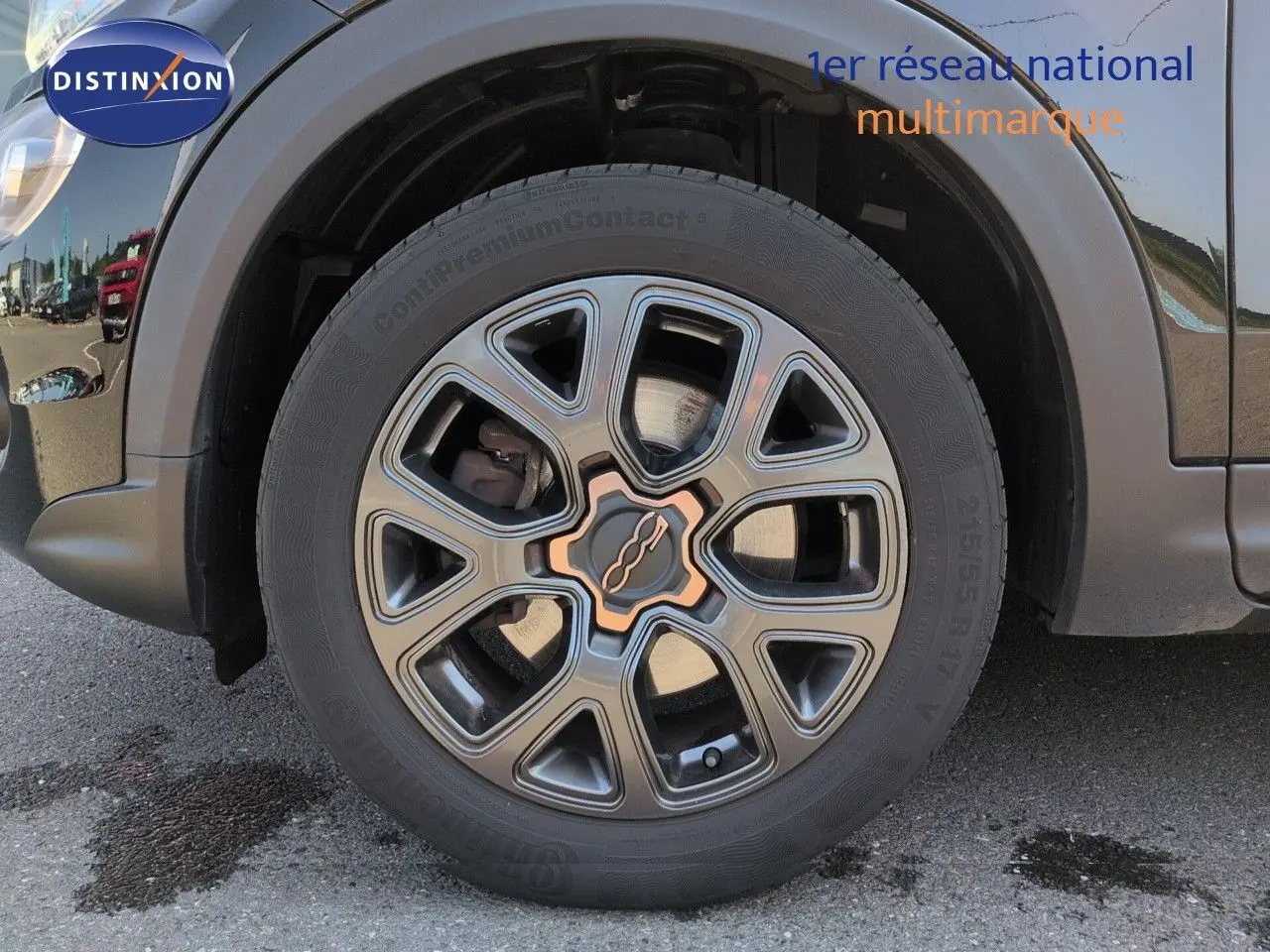 Gros plan sur la roue avant gauche de la Fiat 500X noire avec jante alu bronze du Pack Style.