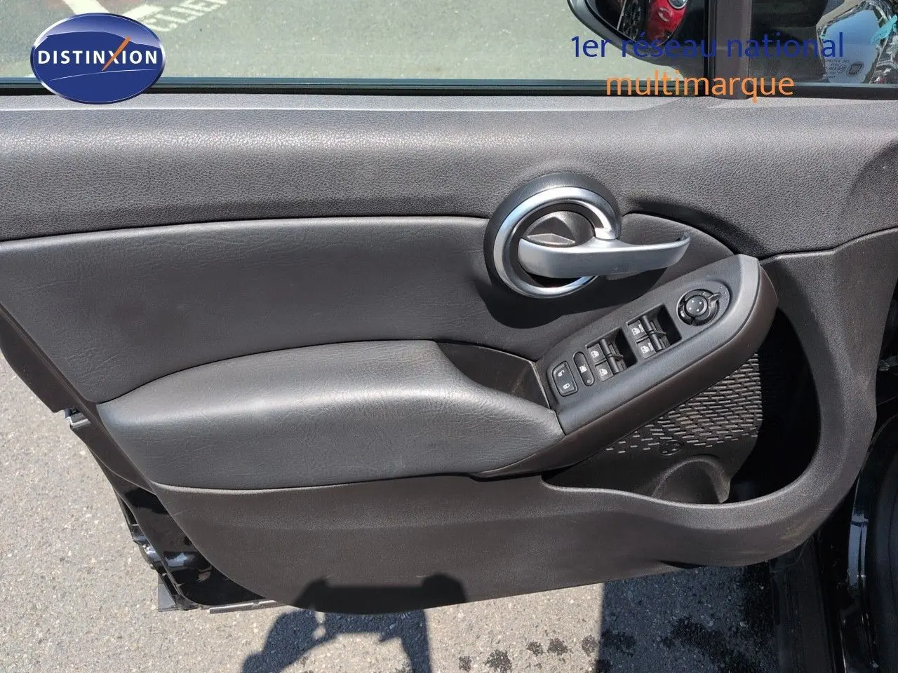 Gros plan sur la porte avant gauche noire avec commandes électriques et poignée argentée du Fiat 500X 2018.