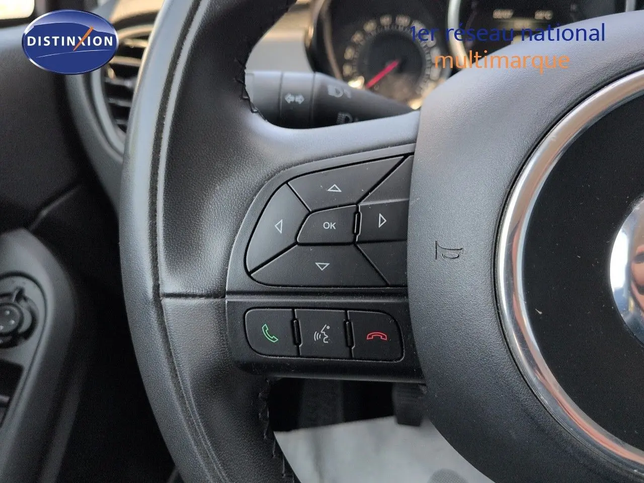 Gros plan sur le volant cuir multifonction noir du Fiat 500X avec commandes audio et téléphone intégrées.