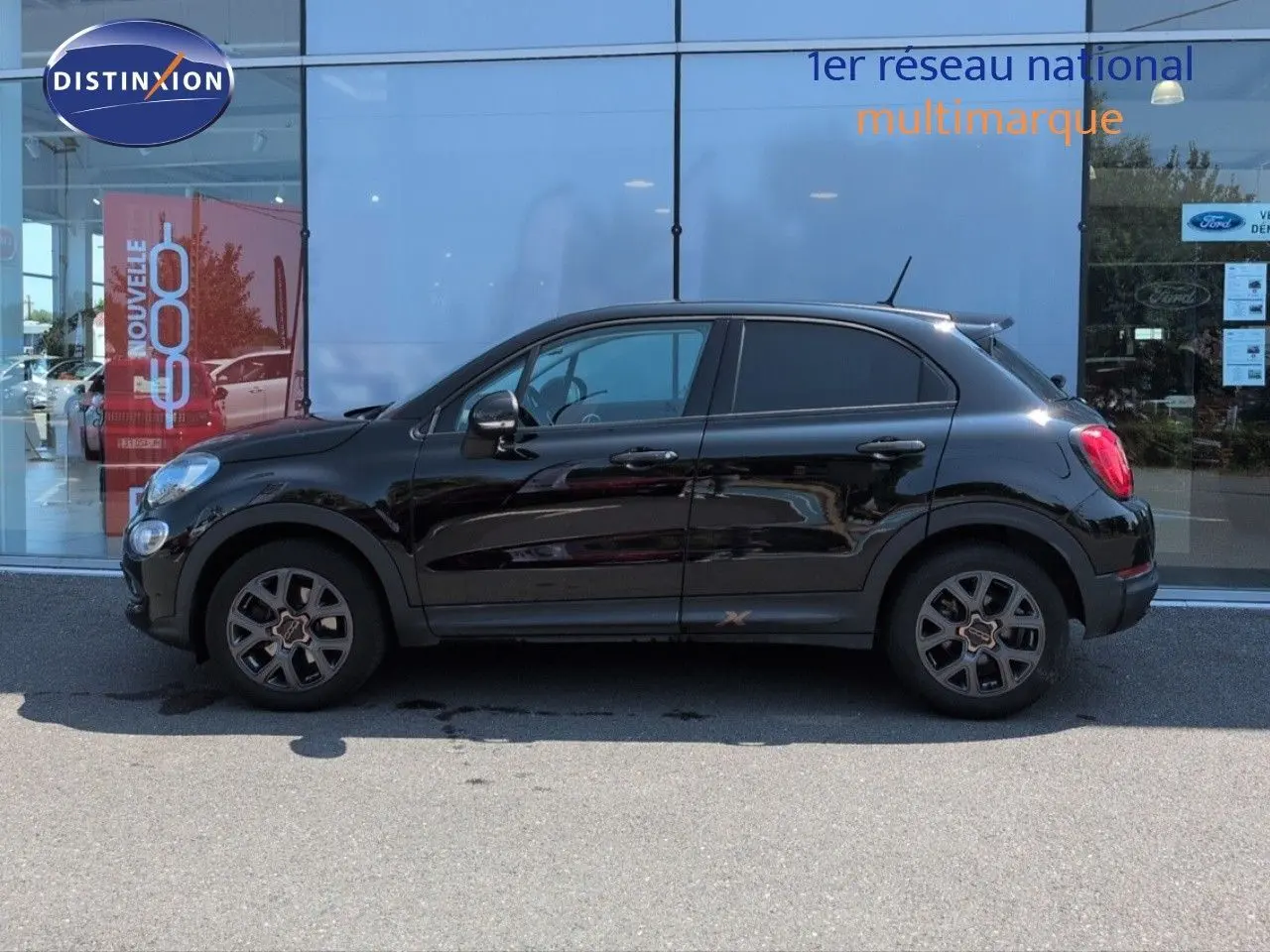 Profil côté gauche d'un FIAT 500X noir Cinéma pastel, avec jantes alu et becquet arrière visible.