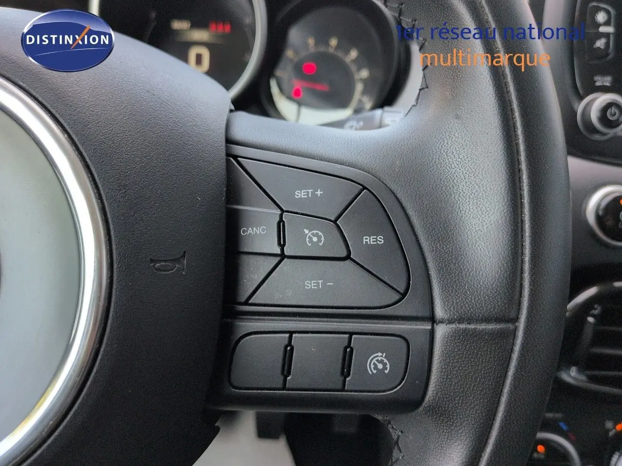 Gros plan sur le volant cuir noir multifonction du Fiat 500X 2018 avec commandes de régulateur de vitesse.