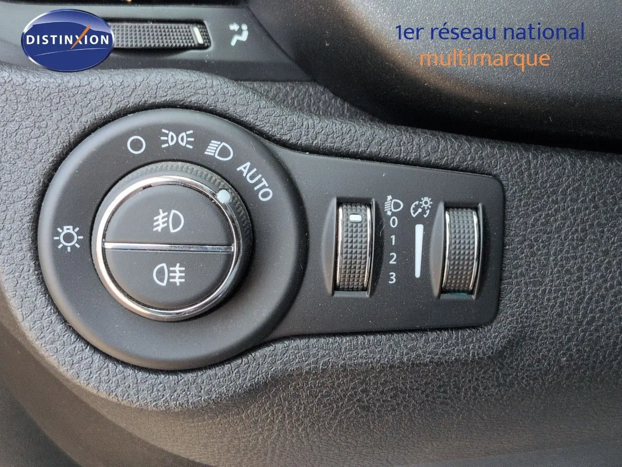 Gros plan sur les commandes d’éclairage et réglages du tableau de bord noir du Fiat 500X 2018.