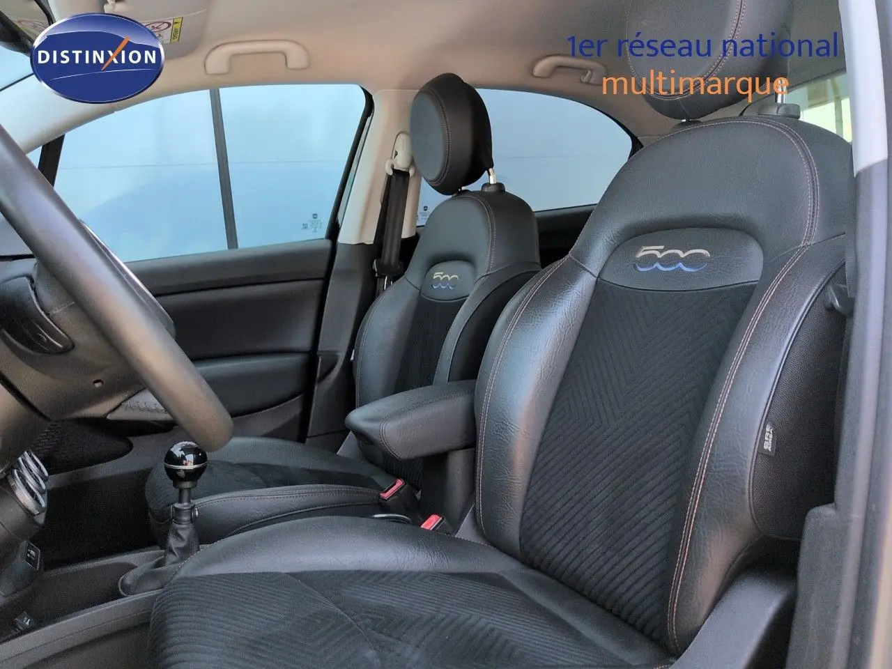 Vue intérieure côté conducteur du Fiat 500X 2018, sellerie cuir noir avec logo 500 brodé sur les appuie-têtes.