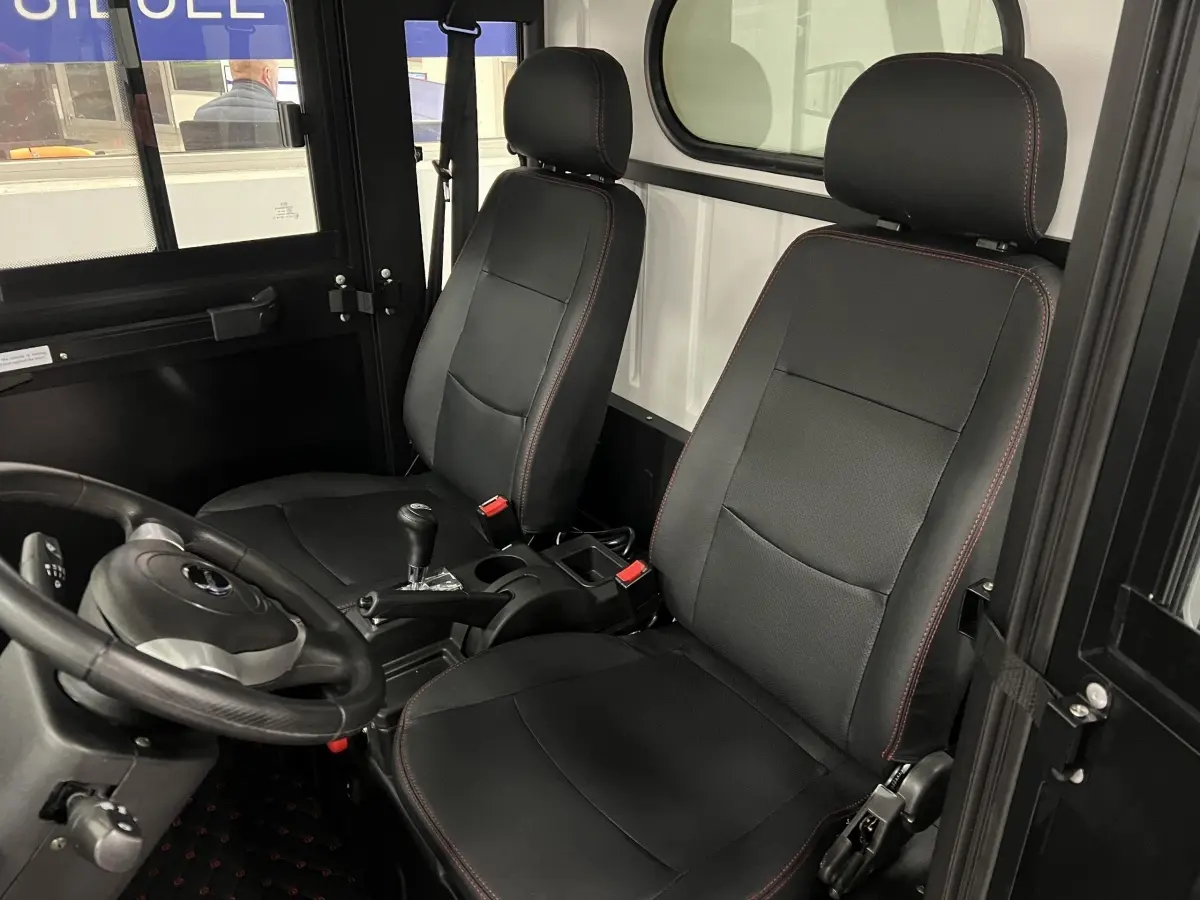 Intérieur de la LIBERTY L7e H2 CARGO 2025 vu côté conducteur, sièges noirs avec surpiqûres rouges et vitre arrière blanche.