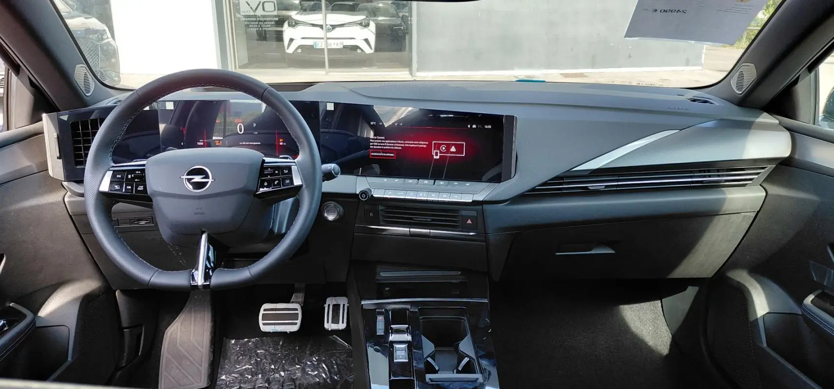 Vue intérieure avant de l’Opel Astra 2025 noire, mettant en valeur le tableau de bord numérique et la console centrale moderne.