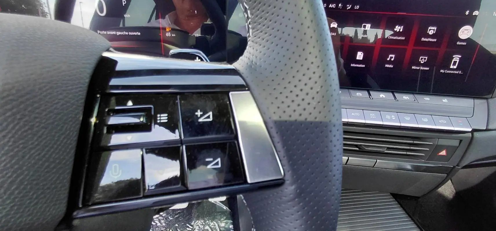 Gros plan sur le volant perforé et les commandes intégrées côté gauche de l’Opel Astra 2025 avec tableau de bord numérique.