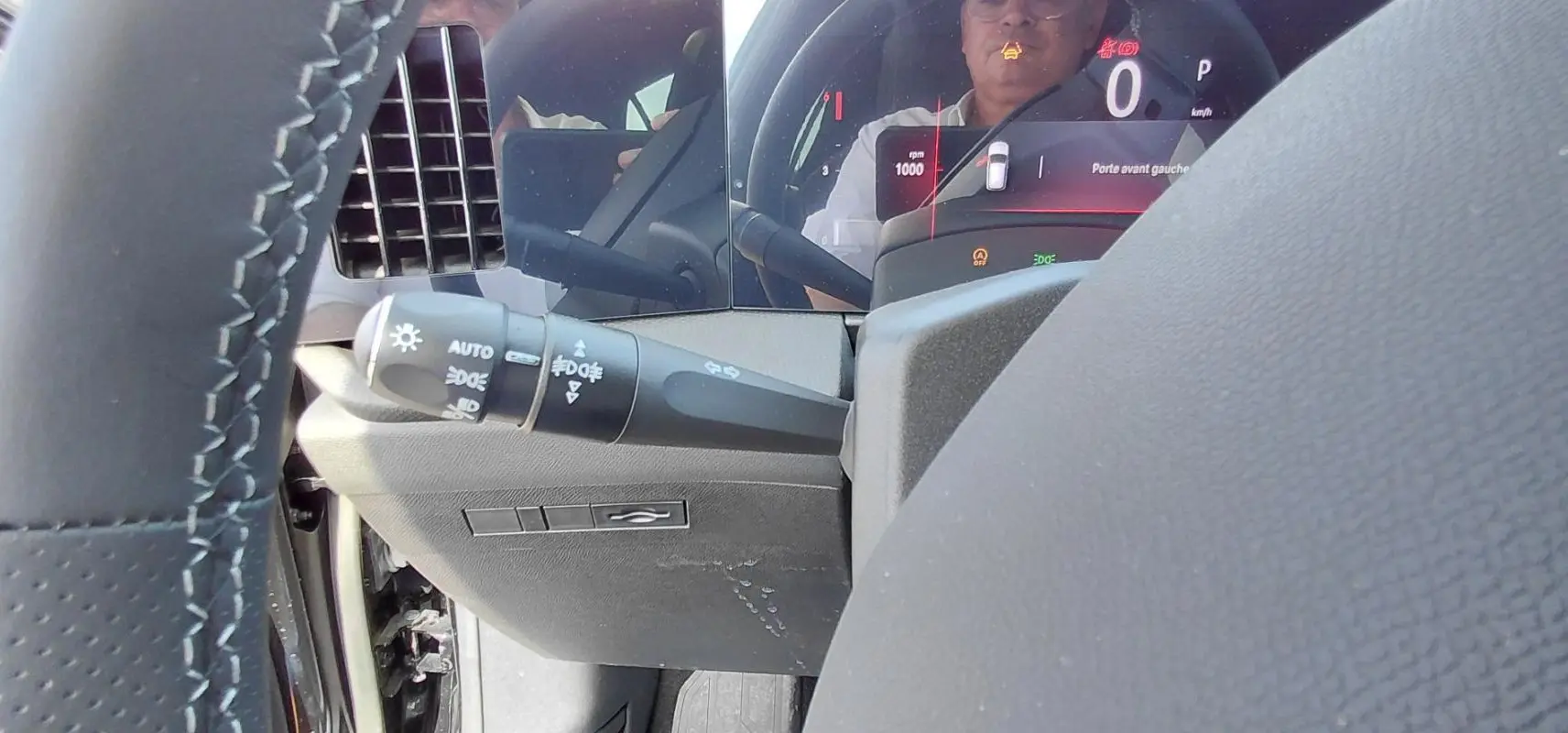 Gros plan sur la commande des feux et le tableau de bord numérique noir de l'Opel Astra 2025 Diesel, côté gauche.