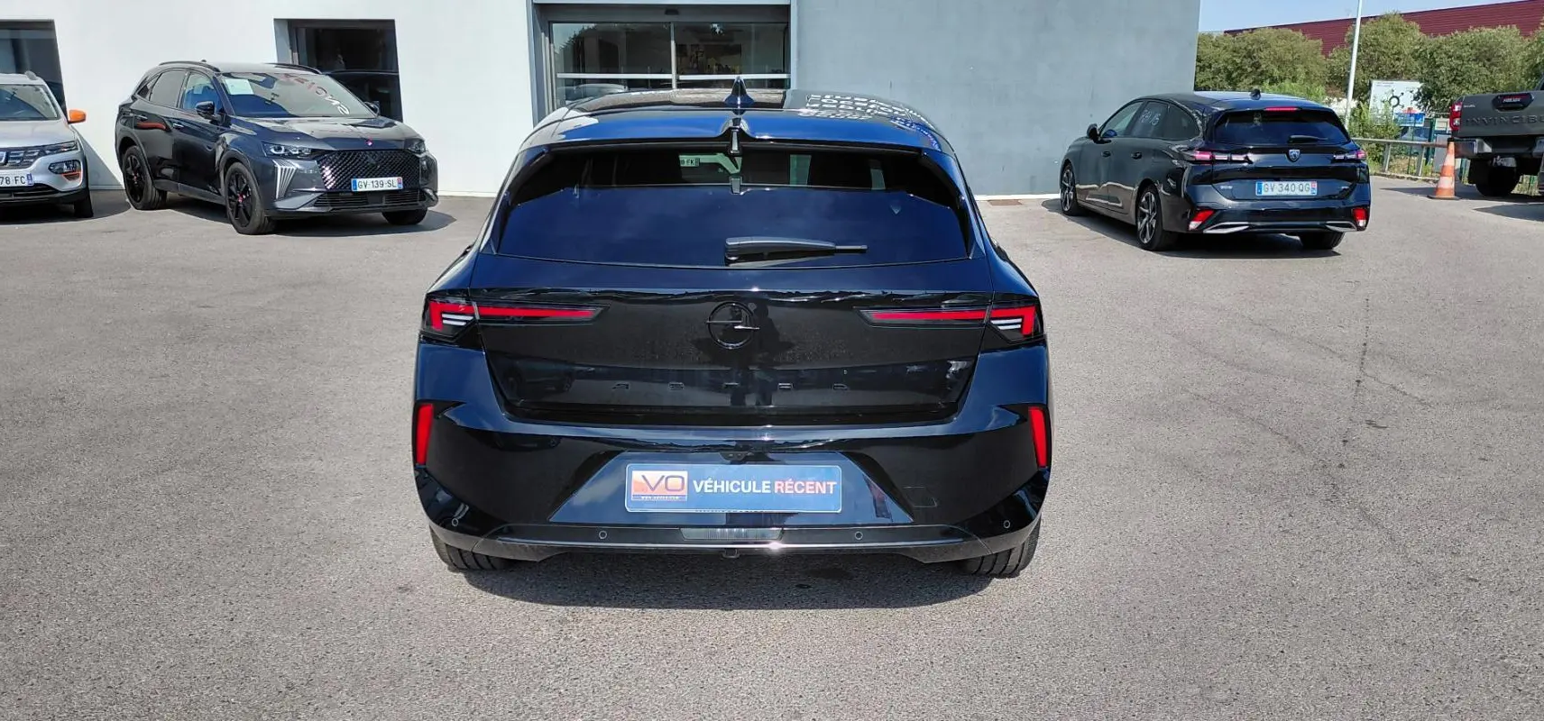 Vue arrière d'une Opel Astra noire 2025, avec feux arrière fins et plaque "Véhicule récent" visible.