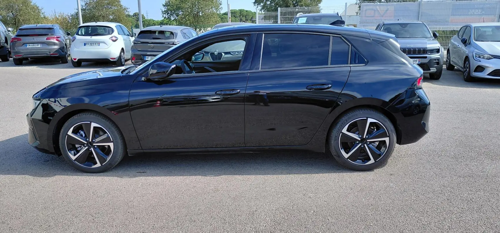 Opel Astra 2025 noire vue de profil côté gauche, avec jantes alliage bicolores et vitres teintées.